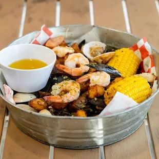a bowl of shrimp, corn, and corn on the cob