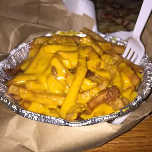 a plate of cheese fries with a fork