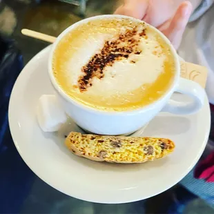a cup of cappuccino and a biscuit