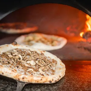 two pizzas cooking in an oven