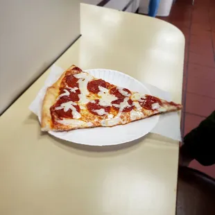 a slice of pepperoni pizza on a paper plate