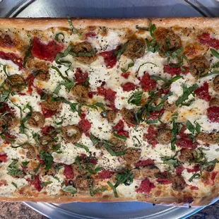 a pizza with meat, cheese, and spinach