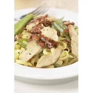 a plate of pasta with chicken and asparagus