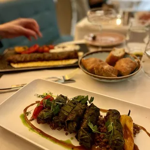 Foreground: Char Grilled Quail Wrapped in Wine Leaves Background: Nar Kebab