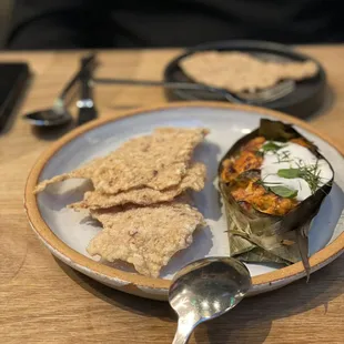 Seafood curry in banana leaf with rice crackers