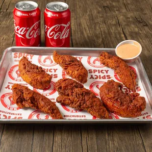 a tray of fried chicken and two cans of coke