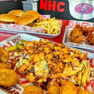 two trays of fried chicken and two trays of macaroni and cheese fries