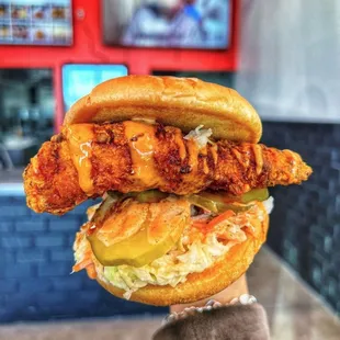 a hand holding a chicken sandwich