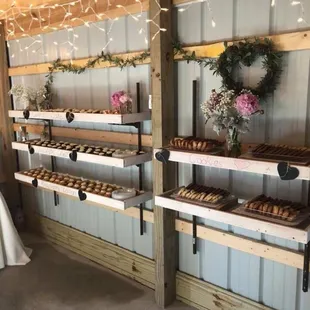 a bride and groom standing in front of shelves of pastries
