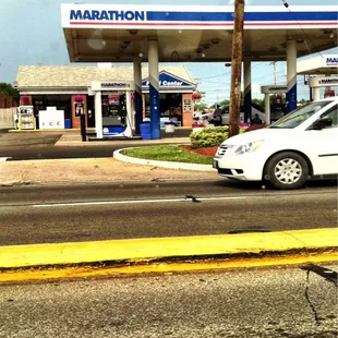 a white car parked in front of a gas station