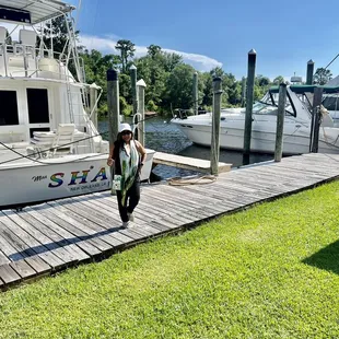 a woman walking on a dock with boats in the background