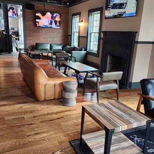 a living room with couches, tables, and televisions
