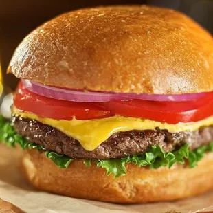 a hamburger with cheese, tomato, and lettuce