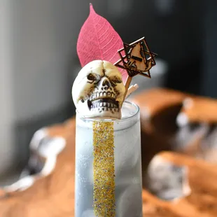 a skull on a stick in a tall glass