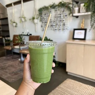 a hand holding a green smoothie