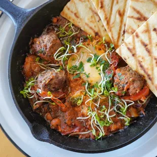 Lamb Shakshuka 
 made with 6oz homemade Lamb Meatballs, Soft Cooked Egg,Tomato Sauce, Roasted Peppers, Eggplant and Homemade Pita Bread