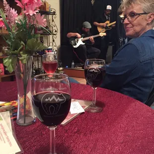 a woman sitting at a table with a glass of wine