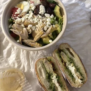a bowl of salad, a sandwich, and a glass of wine