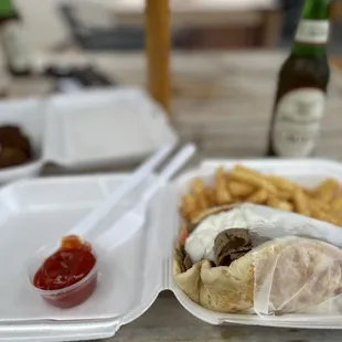  a sandwich and fries in a styrofoam container