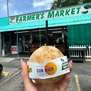 a person holding a sandwich in front of a store