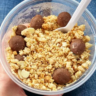 a person holding a bowl of cereal and chocolate balls