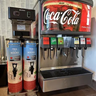 a coca cola machine and two cans of soda