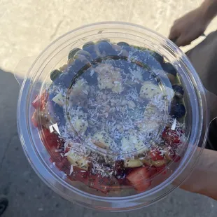 a person holding a plastic container of fruit