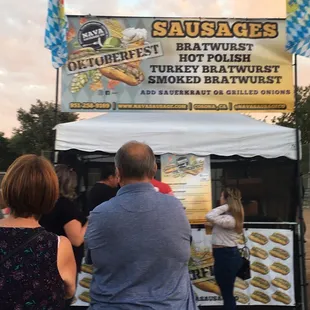 people standing in front of a sausage stand