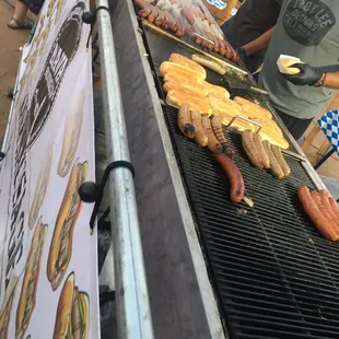 people cooking hotdogs on a grill