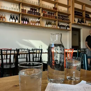 two glasses of water and a pitcher on a table
