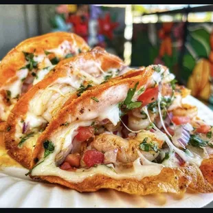 Grilled shrimp tacos with melted cheese diced tomatoes red onion cilantro and our chipotle mayo spread