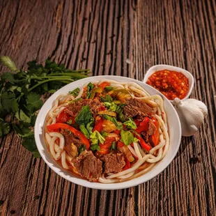 Lagman-Pulled noodles topped with stir-fried meat and seasoned vegetables.