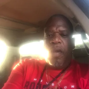 a man in a red shirt sitting in a car