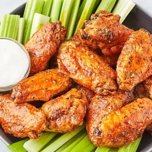 a plate of buffalo wings with celery sticks