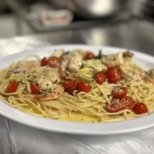 a plate of pasta with shrimp and tomatoes