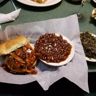 Chicken sandwich with baked beans and a side of the greens it&apos;s a shame it looks so good because the taste was just okay