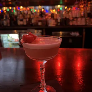 a drink in a coupe glass with a cherry garnish