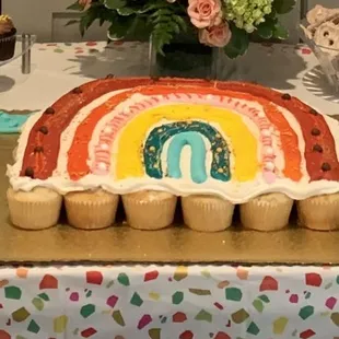 a rainbow cake and cupcakes