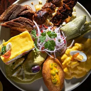 Peruvian food sampler :causa de pollo rellena,tamal,chicken brocheta,pork chuleta,with onions sarsa