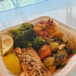 a plate of fish, vegetables and a lemon