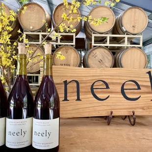 three bottles of wine in front of barrels