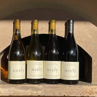 three bottles of wine in front of a brick oven