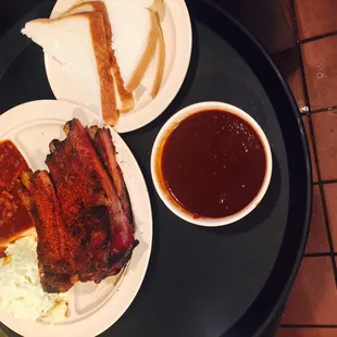 ows a plate of ribs, coleslaw, and a side of coleslaw