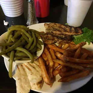 Grilled pork chops with fries and green beans.