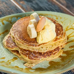 a stack of pancakes with bananas and syrup