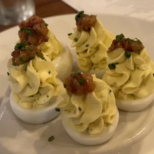 a plate of deviled eggs with bacon and chives