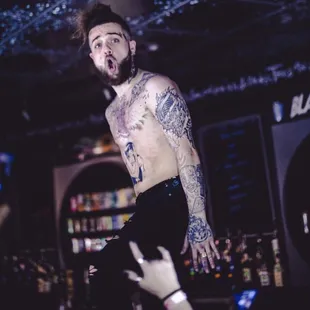 a man with a tattoo on his chest standing in front of a crowd