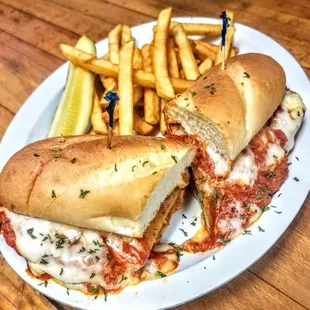 Homemade baked eggplant Parmesan sandwich served with a side of french fries