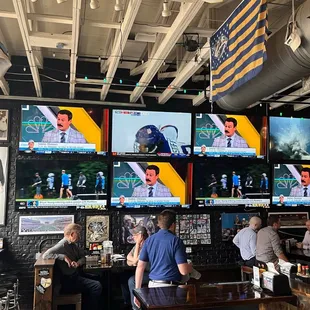 people sitting at a bar watching televisions