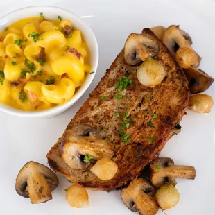 a piece of meat with mushrooms and macaroni and cheese